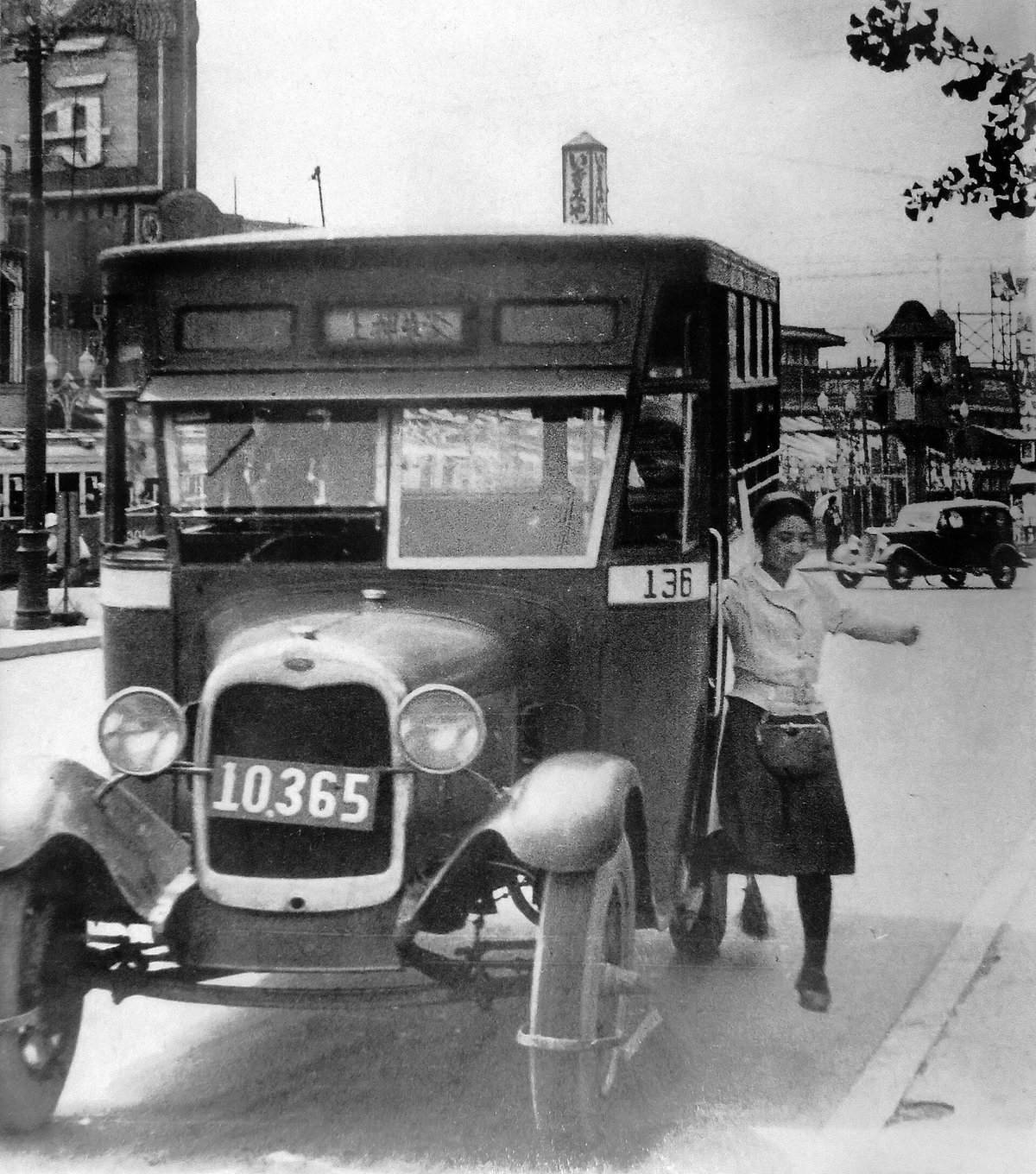 バスの横に立つ女性車掌(昭和9年)。こちらは東京乗合自動車(青バス)で、襟の色から「白襟嬢」と呼ばれた。市営バスの車掌は「赤襟嬢」。(撮影:石川光陽/パブリックドメイン, via Wikimedia Commons)