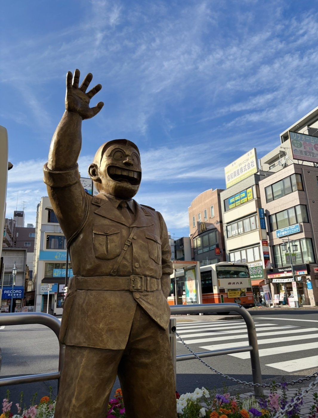 亀有駅前に立つ両さんの銅像。元気よく手を挙げて、町を行き交う人を迎えている。