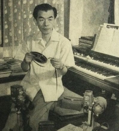 古関裕而(1956年)。(Photo: 朝日新聞社『アサヒグラフ』1956年9月23日号 / パブリックドメイン, via Wikimedia Commons)