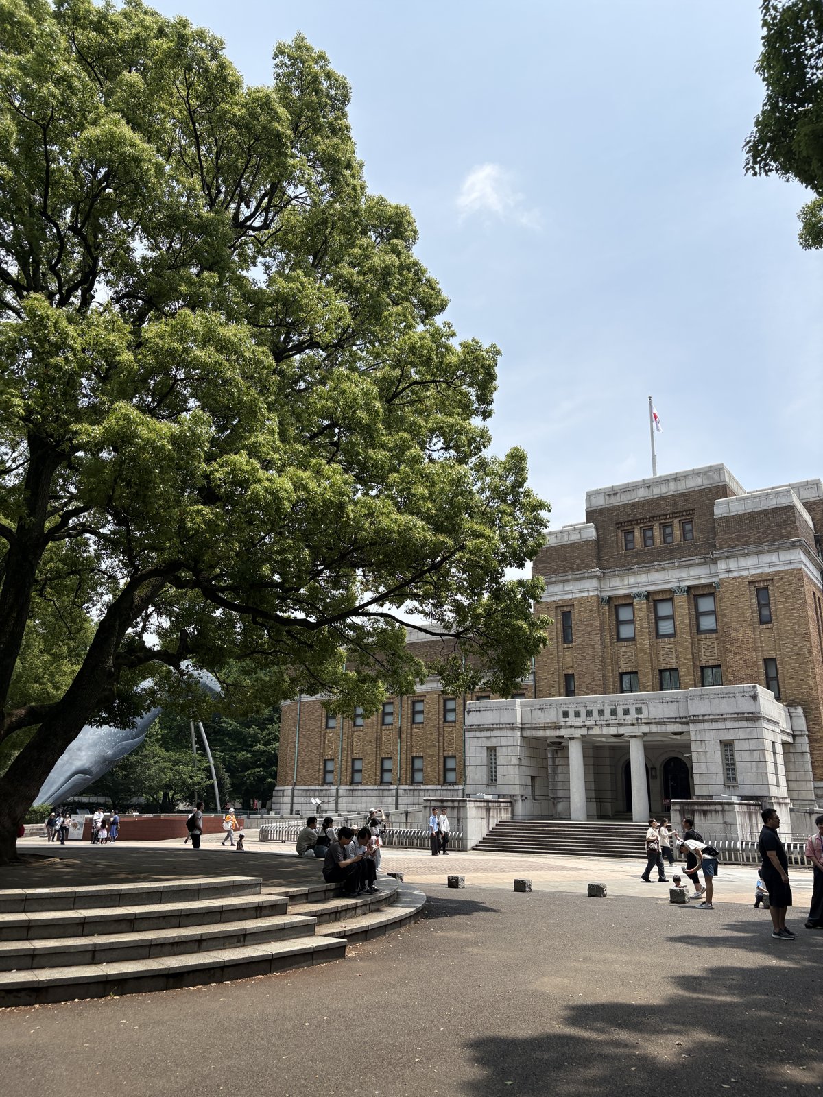国立科学博物館の前。大きな楠が枝を広げる広場。この一帯が、子規たちがボールを追った「博物館横の空き地」にあたる。