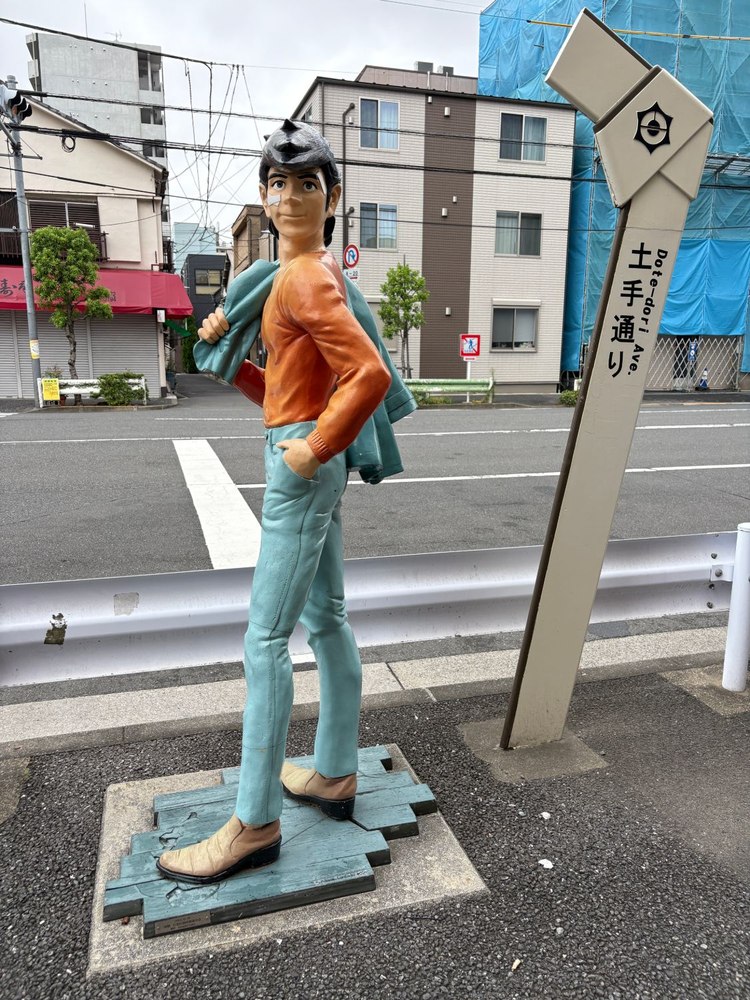 「土手通り」の標柱と矢吹丈。泪橋の交差点へ続く、いろは会商店街の入口に立っている。(筆者撮影)